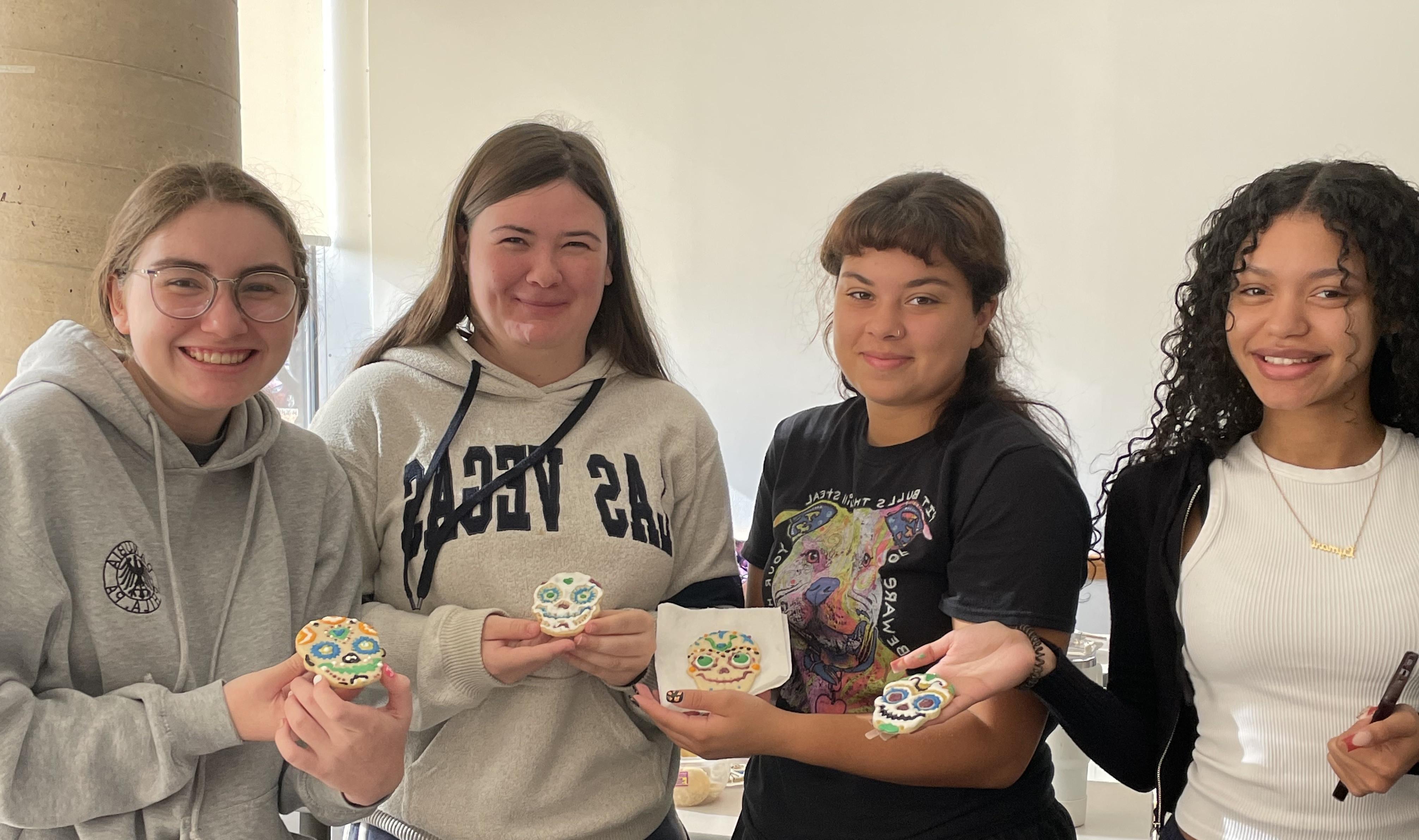 Four students decorate cookies for Day of the Dead.